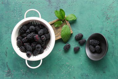 Yeşil arka planda taze böğürtlenli kolaçan ve kase