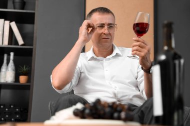 Yetişkin bir adam evde şarap tadıyor.