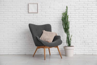 Beyaz tuğla duvarın yanında koltuğu olan büyük bir kaktüs.