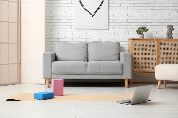 Interior of living room with sofa, yoga equipment and laptop