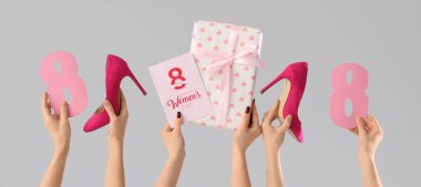 Hediyeli kadın elleri, tebrik kartı ve gri arka planda yüksek topuklu ayakkabılar. Uluslararası Kadınlar Günü için Alışveriş