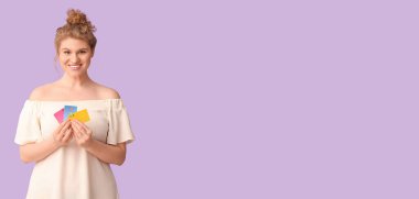 Leylak arka planında kredi kartları olan mutlu genç bir kadın.