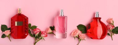 Parfüm şişeleri ve pembe arka planda gül çiçekleri.