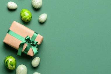 Yeşil arka planda Paskalya yumurtaları olan hediye kutusu.