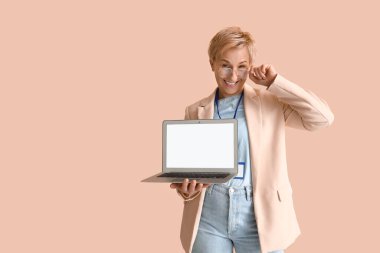 Bej arka planda dizüstü bilgisayarı olan olgun bir kadın programcı.