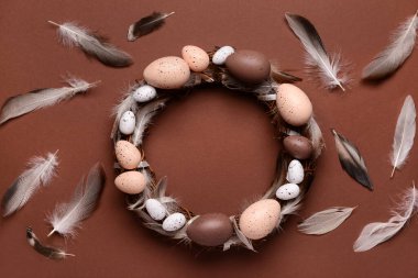 Kahverengi arka planda yumurta ve tüylü Paskalya çelengi