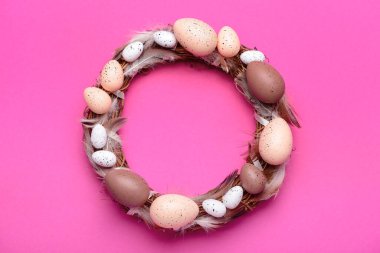 Pembe arka planda yumurta ve tüylü Paskalya çelengi