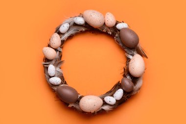 Turuncu arka planda yumurta ve tüylü Paskalya çelengi