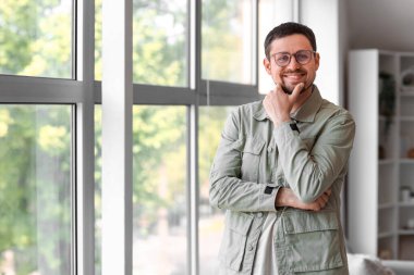 Evin penceresinin yanında şık gözlüklü yakışıklı bir adam.