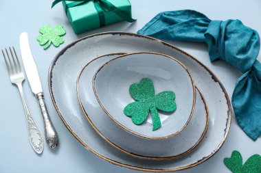 Beautiful table setting for St. Patrick's Day celebration on blue background