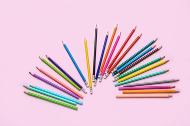 Açık pembe arka planda renkli kalemler grubu