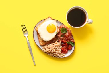 Lezzetli İngiliz kahvaltı tabağı ve sarı arka planda bir fincan kahve.