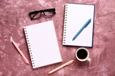 Gözlüklü defterler ve mor arka planda bir fincan lezzetli kahve.