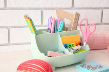 Aydınlık ahşap masa üzerinde farklı kırtasiye malzemesi olan tutucu, yakın çekim