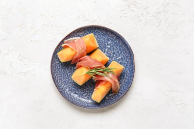 Lezzetli kavunlu tabak ve arka planda jambon.