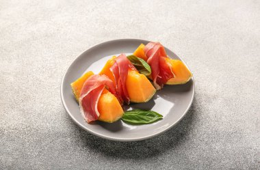 Lezzetli kavun, jambon ve arkaplanda fesleğen.