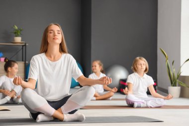 Beden eğitiminde meditasyon yapan bir grup küçük çocukla yoga eğitmeni.