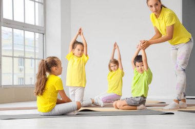 Eğitmeni olan bir grup küçük çocuk spor salonunda yoga yapıyor.