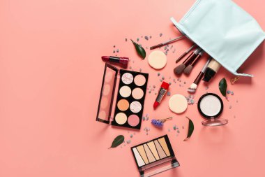 Makyaj ürünleri ve mercan arka planda güzel çiçeklerle süslü şık bir makyaj çantası.