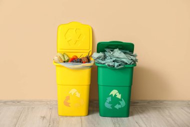 Bej duvarın yanında farklı çöp kutuları var. Geri dönüşüm kavramı