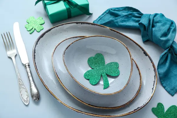 Beautiful table setting for St. Patrick's Day celebration on blue background