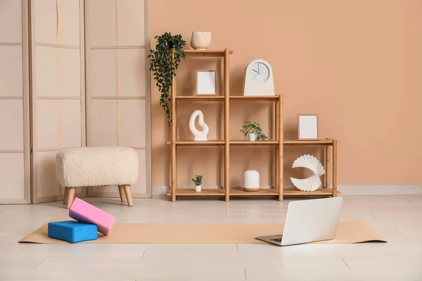 Interior of living room with yoga blocks, mat and laptop