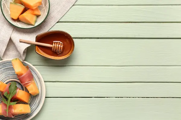 Yeşil ahşap zemin üzerinde prosciutto ve roka ile lezzetli kavun tabağı