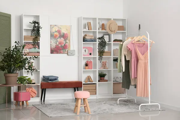 Interior of modern dressing room with clean clothes hanging on rack