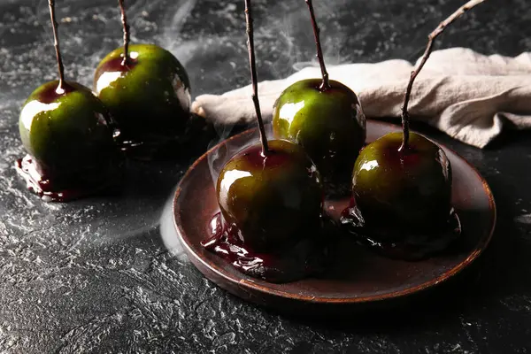 Siyah arka planda Cadılar Bayramı için lezzetli karamelli elma tabağı.