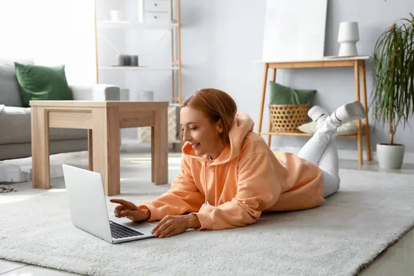 Mature woman in hoodie using laptop at home