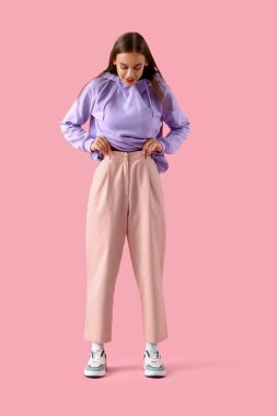 Pembe arka planda kapüşonlu genç kadın.