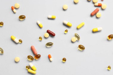 Balık yağı kapsülleri ve gri arka planda farklı haplar.