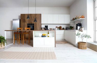 Modern mutfak, beyaz mobilyalar ve ahşap ada masası.