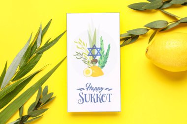 Dört tür (lulav, hadas, arava, etrog) ve sarı arkaplanda Mutlu SUKKKOT yazılı tebrik kartı