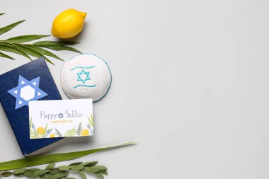Dört türün (lulav, hadas, arava, etrog) yer aldığı Sukkot festivali kompozisyonu, Tevrat ve gri arkaplan üzerindeki tebrik kartı