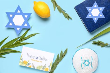 Dört türden (lulav, hadas, arava, etrog) oluşan Sukkot festivali kompozisyonu, Tevrat ve mavi zemin üzerindeki tebrik kartı