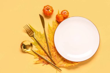 Sarı arka planda akçaağaç yaprağı ve balkabağı ile sonbahar masası ayarları