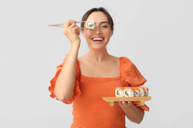 Hafif arka planda lezzetli suşisi olan mutlu genç bir kadın.