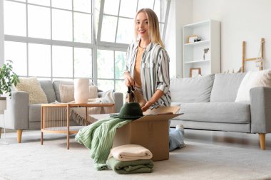 Evde çizmeleri kutuya koyan genç bir kadın.