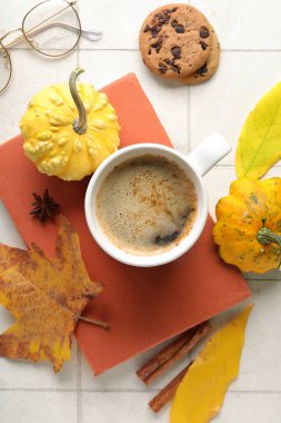 Hafif fayans zemininde aromatik kahve, kitap ve sonbahar dekoru içeren kompozisyon