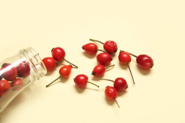 Sarı arka planda taze gül kalçası böğürtlenli şişe