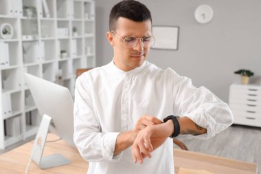 Ofisteki saate bakan yakışıklı genç adam.