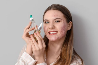 Sivilceli genç bir kadın ve arka planda bir şişe serum, yakın plan.