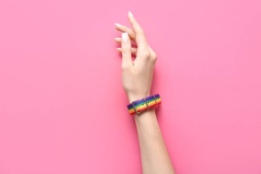 Pembe arka planda gökkuşağı bileziği olan kadın. LGBTQ kavramı