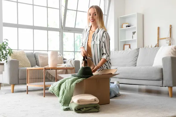 Evde çizmeleri kutuya koyan genç bir kadın.