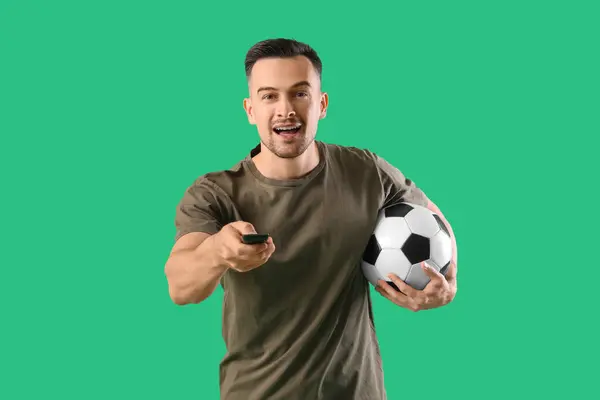 Glücklicher Junger Mann Mit Ball Beobachtet Fußballspiel Auf Grünem Hintergrund — Stockfoto