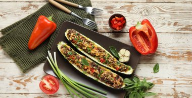 Doldurulmuş kabak tekneleri ve hafif ahşap arka planda taze sebzeler.