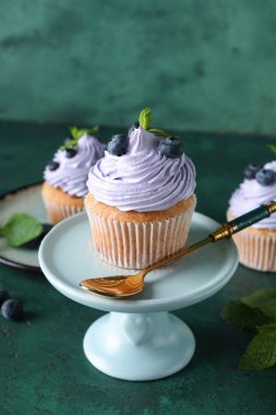 Yeşil zemin üzerinde yabanmersinli ve nane aromalı lezzetli bir kek standı.