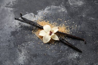 Aromatik vanilya şekeri, çiçek ve siyah arkaplanda çubuklar