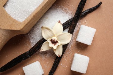 Aromatik vanilya şekeri, çiçek ve kahverengi arka planda çubuklar